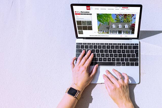 Hands on laptop, using GAF Virtual Remodeler, where you can see new shingles on your home. 